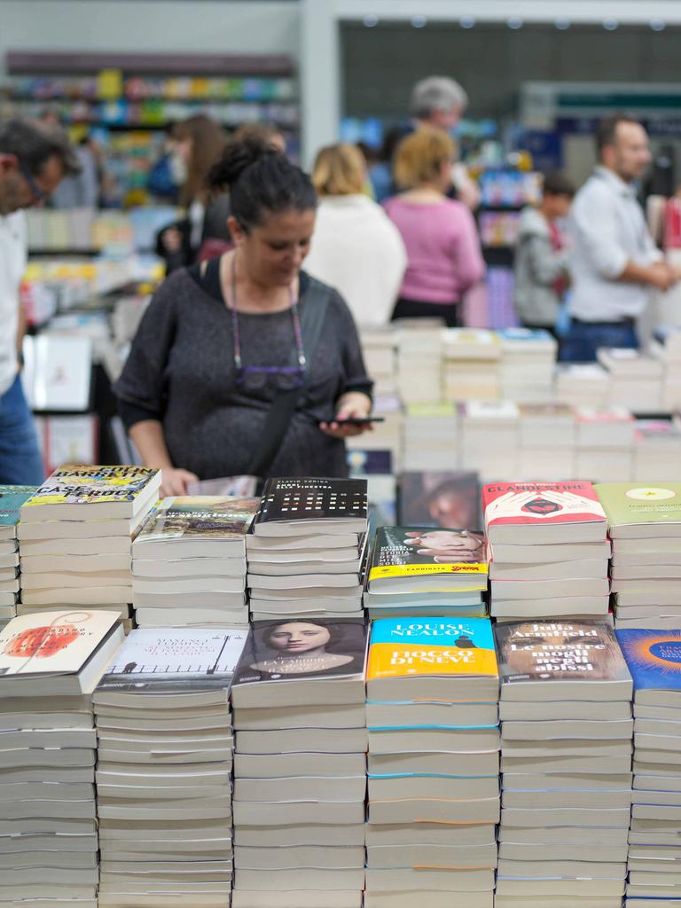 Besucher streifen um Stände mit Bücherstapeln herum.