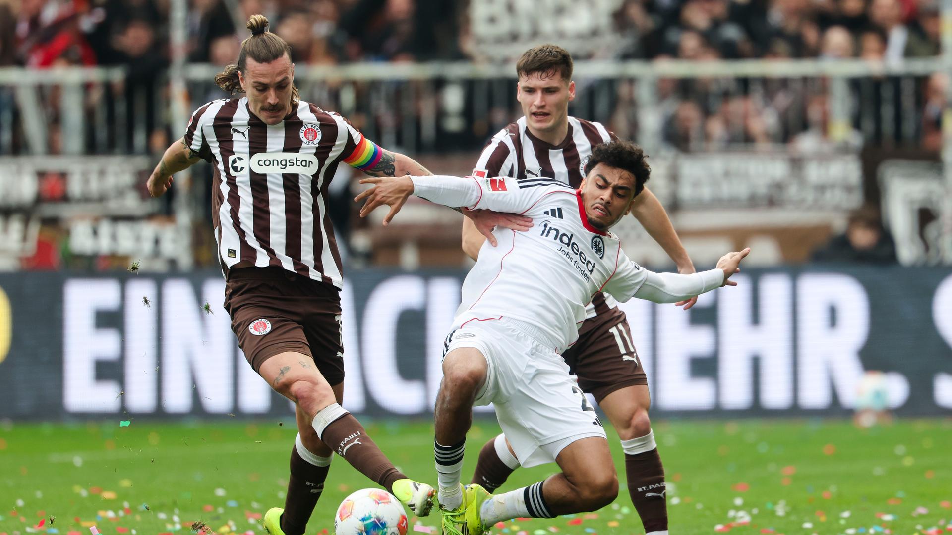 Frankfurts Spieler Nathaniel Brown kämpft mit Jackson Irvine und Arkadiusz Pyrka von St. Pauli um den Ball. 