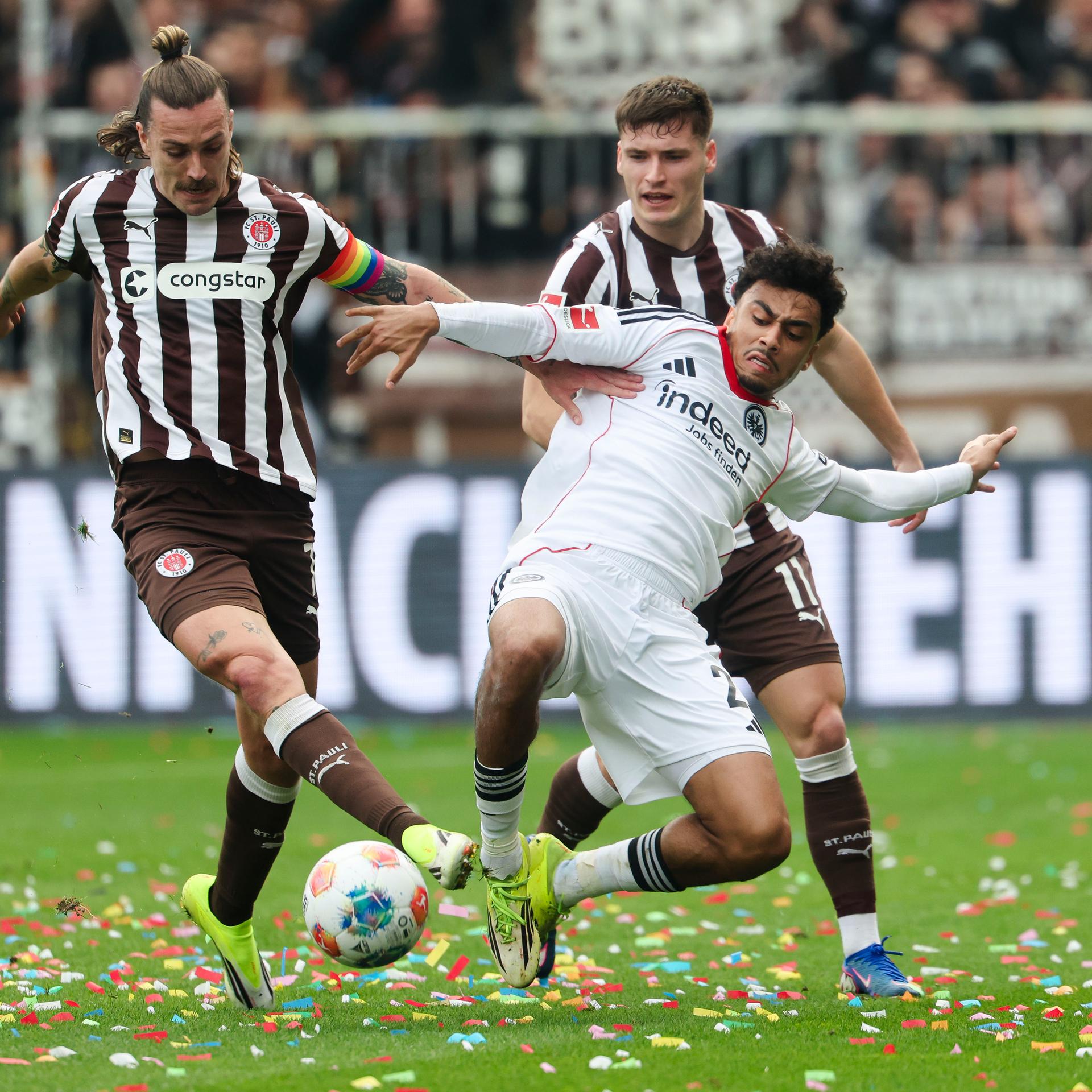 Frankfurts Spieler Nathaniel Brown kämpft mit Jackson Irvine und Arkadiusz Pyrka von St. Pauli um den Ball. 