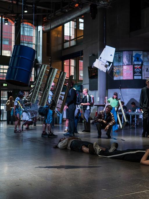 Gruppen von stehenden und liegenden Musikern und Besuchern bevölkern den Konzertsaal der Centralstation in Darmstadt.
