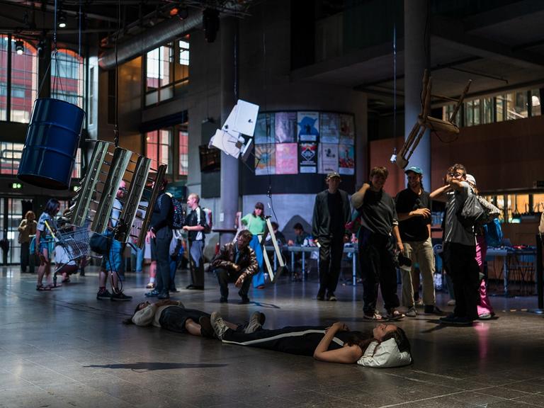 Gruppen von stehenden und liegenden Musikern und Besuchern bevölkern den Konzertsaal der Centralstation in Darmstadt.