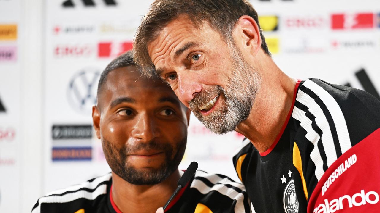 Jürgen Klopp (r.) beugt sich zu Jonathan Tah vor und spricht in sein Mikrofon.