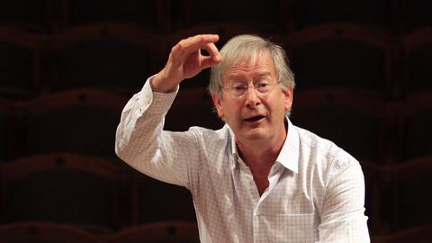 Der Dirigent Sir John Eliot Gardiner hebt die Arme zum Dirigat bei einer Probe. 