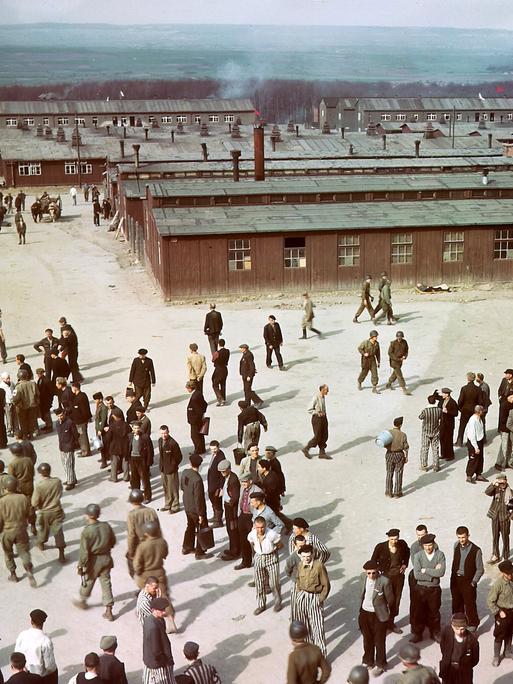 Luftaufnahme des Konzentrationslagers Buchenwald mit Baracken im Hintergrund. Auf einem Hof stehen ehemalige Häftlinge und US-Soldaten. Luftaufnahme des Konzentrationslagers Buchenwald mit Baracken im Hintergrund. Auf einem Hof stehen ehemalige Häftlinge und US-Soldaten.
