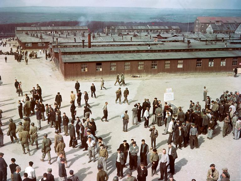 Luftaufnahme des Konzentrationslagers Buchenwald mit Baracken im Hintergrund. Auf einem Hof stehen ehemalige Häftlinge und US-Soldaten. Luftaufnahme des Konzentrationslagers Buchenwald mit Baracken im Hintergrund. Auf einem Hof stehen ehemalige Häftlinge und US-Soldaten.