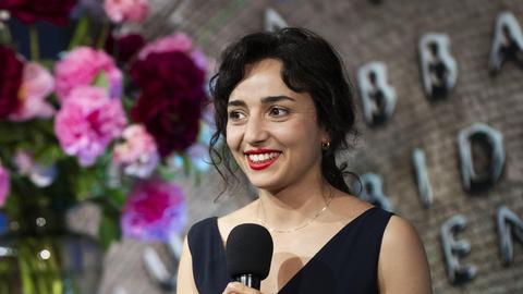 Porträt der niederländischen Schriftstellerin Safae el Khannoussi. Die junge Frau steht im Rahmen einer Preisverleihung im schwarzen Kleid auf einer Bühne.