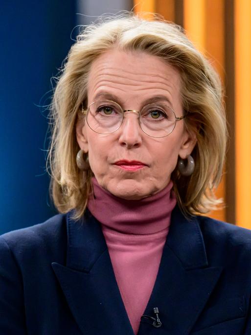Julia Jäkel sitzt in einem Fernsehstudio und schaut direkt in die Kamera. Sie trägt einen Rollkragenpullover in Altrosa und ein dunkelblaues Sakko.