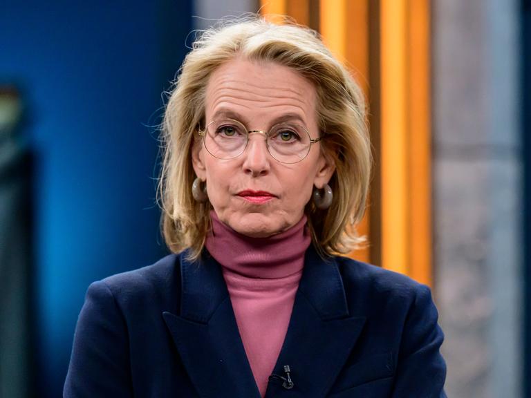 Julia Jäkel sitzt in einem Fernsehstudio und schaut direkt in die Kamera. Sie trägt einen Rollkragenpullover in Altrosa und ein dunkelblaues Sakko.