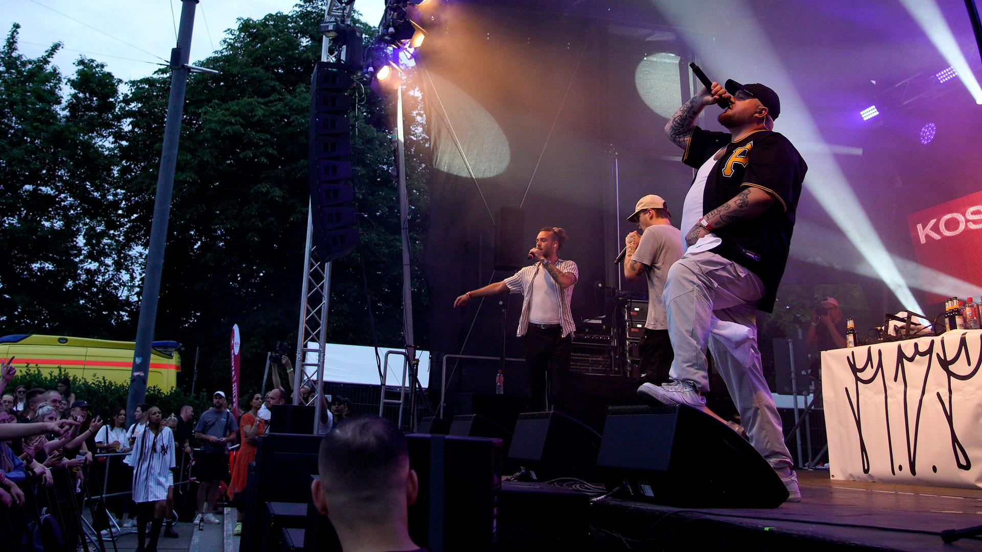 Der Rapper Lugatti steht bei einem Konzert mit einem Mikrofon in der Hand auf der Bühne.