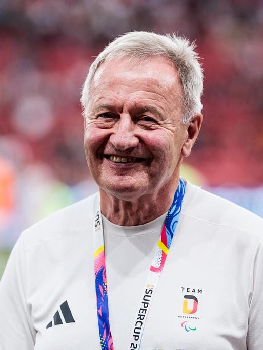 Friedhelm Julius Beucher trägt Sportkleidung und steht in einem Stadion.