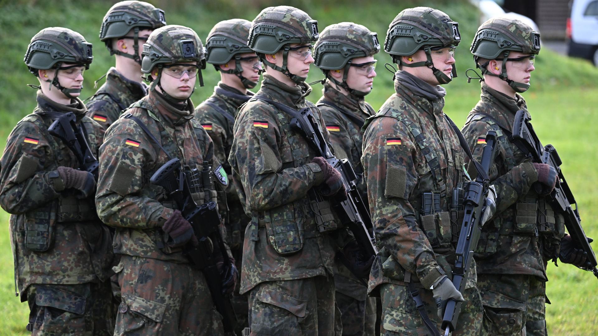 Junge Bundeswehr-Rekturen mit Waffen und Helmen
