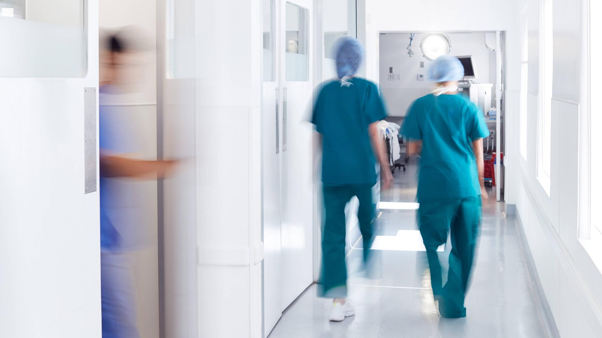 Zwei Krankenpfleger gehen auf dem Flur einer Klinik entlang