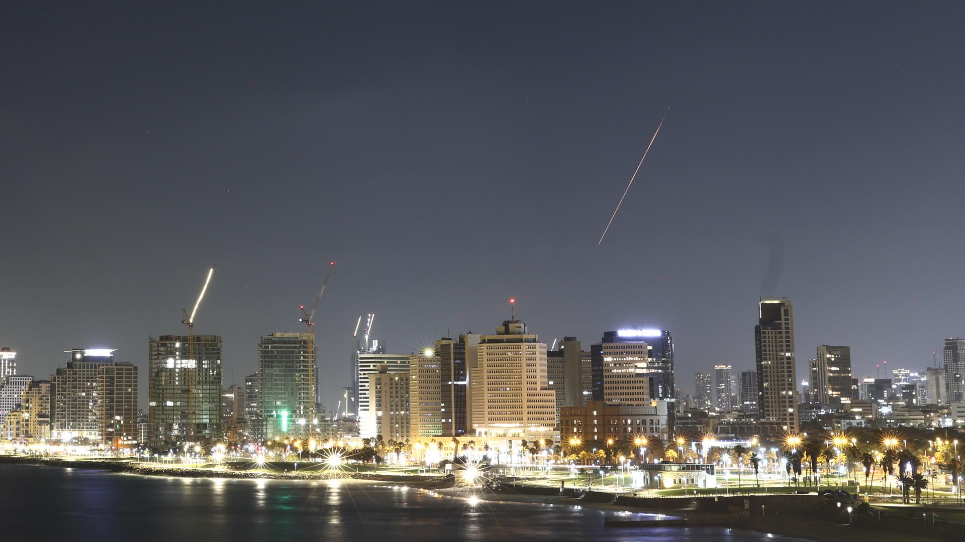 Über dem Nachthimmel von Tel Aviv fängt das Luftabwehrsystem Israels eine Rakete ab, die als heller Streifen zu erkennen ist