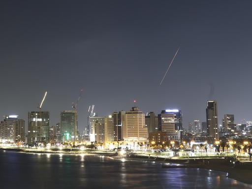 Über dem Nachthimmel von Tel Aviv fängt das Luftabwehrsystem Israels eine Rakete ab, die als heller Streifen zu erkennen ist