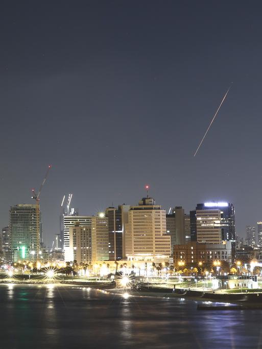 Über dem Nachthimmel von Tel Aviv fängt das Luftabwehrsystem Israels eine Rakete ab, die als heller Streifen zu erkennen ist
