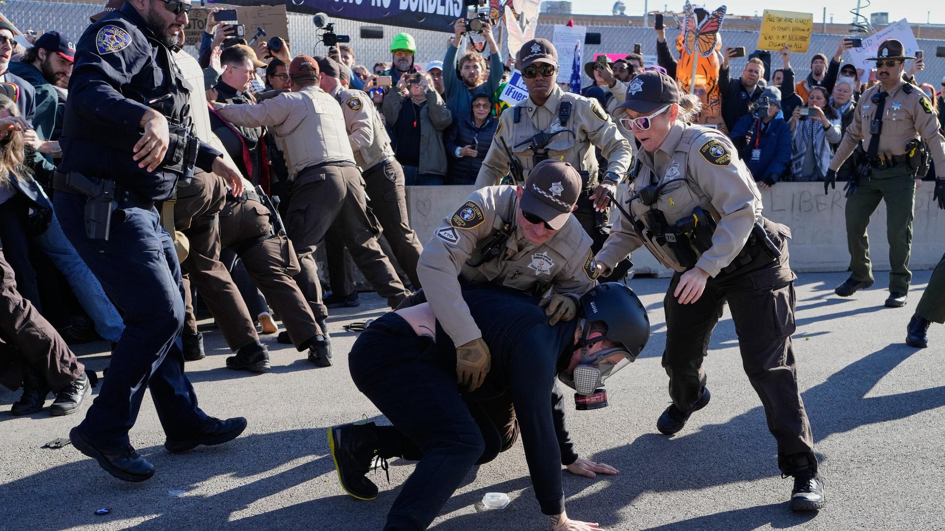 Polizisten nehmen einen Demonstranten vor dem Abschiebezentrum Broadview fest. Dahinter drängen andere Polizisten die Menge zurück.