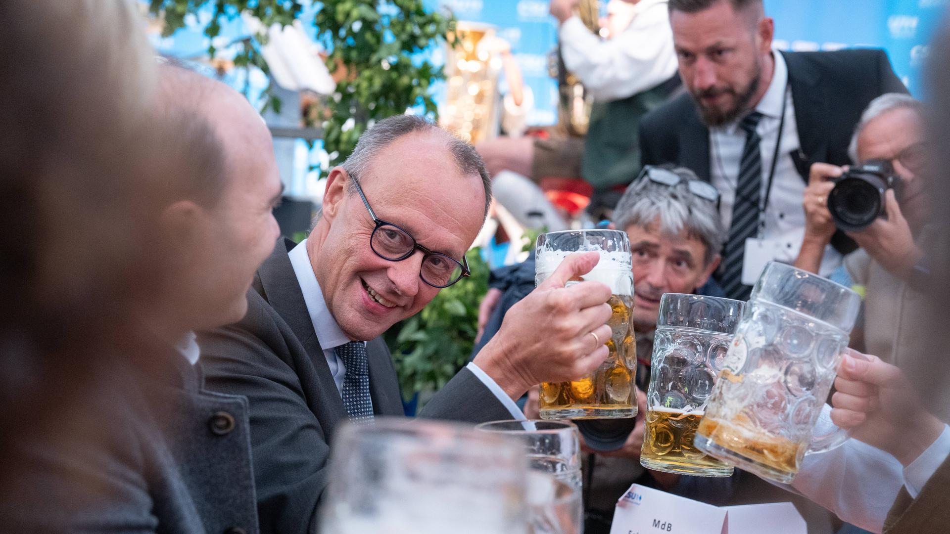 Friedrich Merz, Parteivorsitzender CDU, als Festredner auf der Altdorfer Wiesn in Altdorf bei Landshut stößt mit einer Maß Bier. Um ihn herum weitere Männer mit Bierkrügen und ein Fotograf, der das Schauspiel gekonnt in Szene setzt.