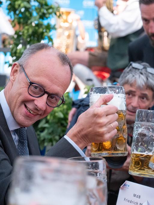 Friedrich Merz, Parteivorsitzender CDU, als Festredner auf der Altdorfer Wiesn in Altdorf bei Landshut stößt mit einer Maß Bier. Um ihn herum weitere Männer mit Bierkrügen und ein Fotograf, der das Schauspiel gekonnt in Szene setzt.