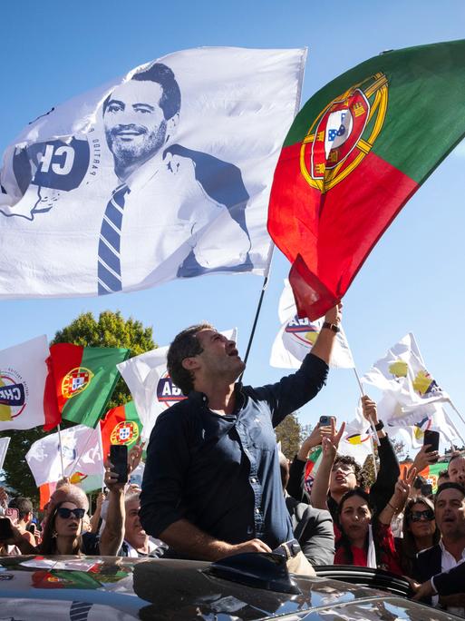 Bei einer Wahlkampfveranstaltung schwenkt Andre Ventura die portugiesische Flagge. Auch viele Flaggen seiner Partei Chega sind zu sehen.