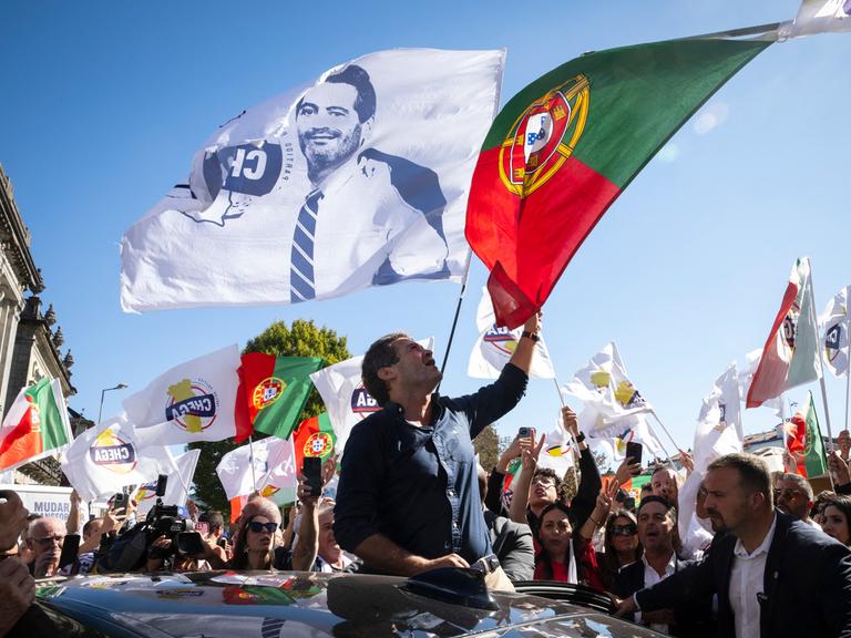 Bei einer Wahlkampfveranstaltung schwenkt Andre Ventura die portugiesische Flagge. Auch viele Flaggen seiner Partei Chega sind zu sehen.