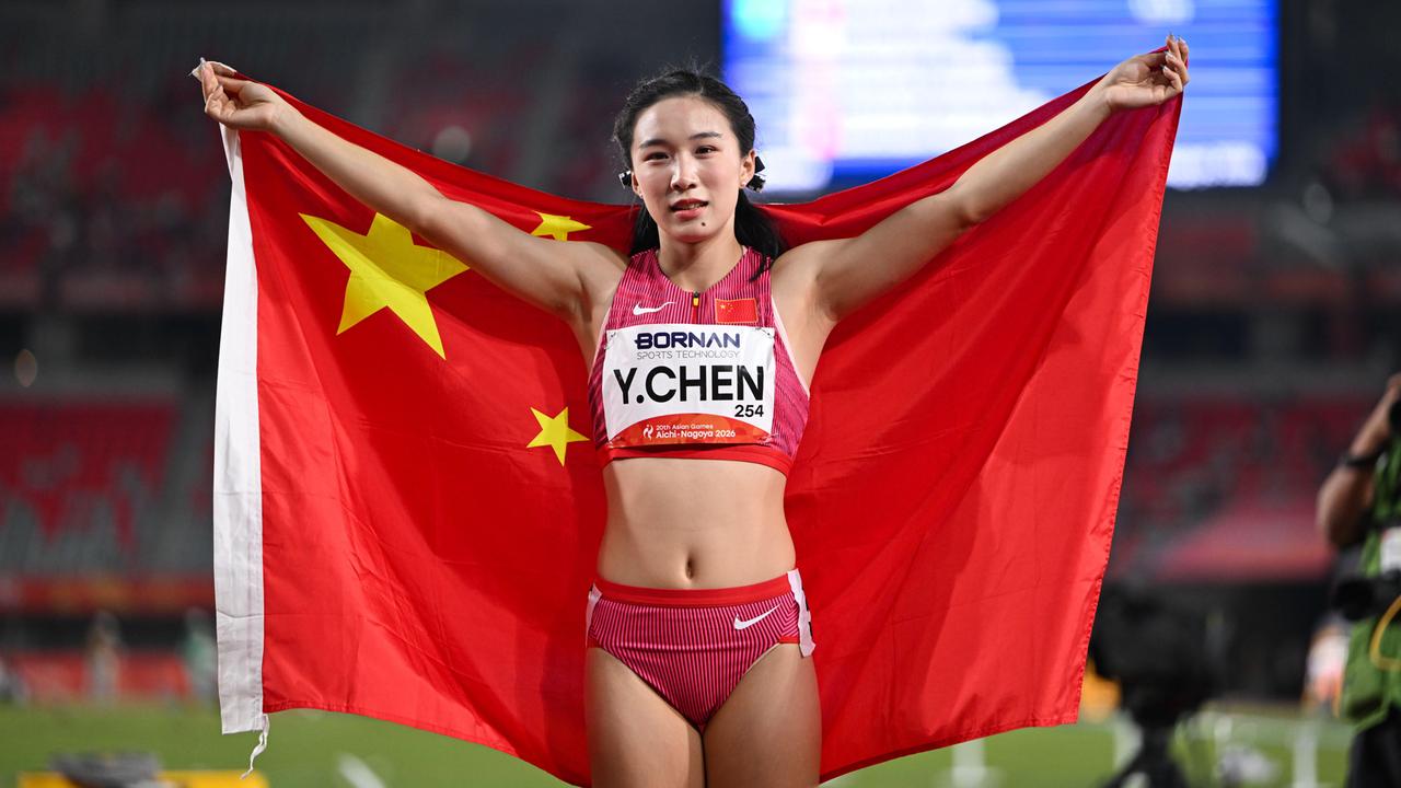 Zu sehen ist die Sprinterin Chen Yujie. Sie trägt die chinesische Nationalflagge über den Schultern und hält sie mit beiden Händen fest.