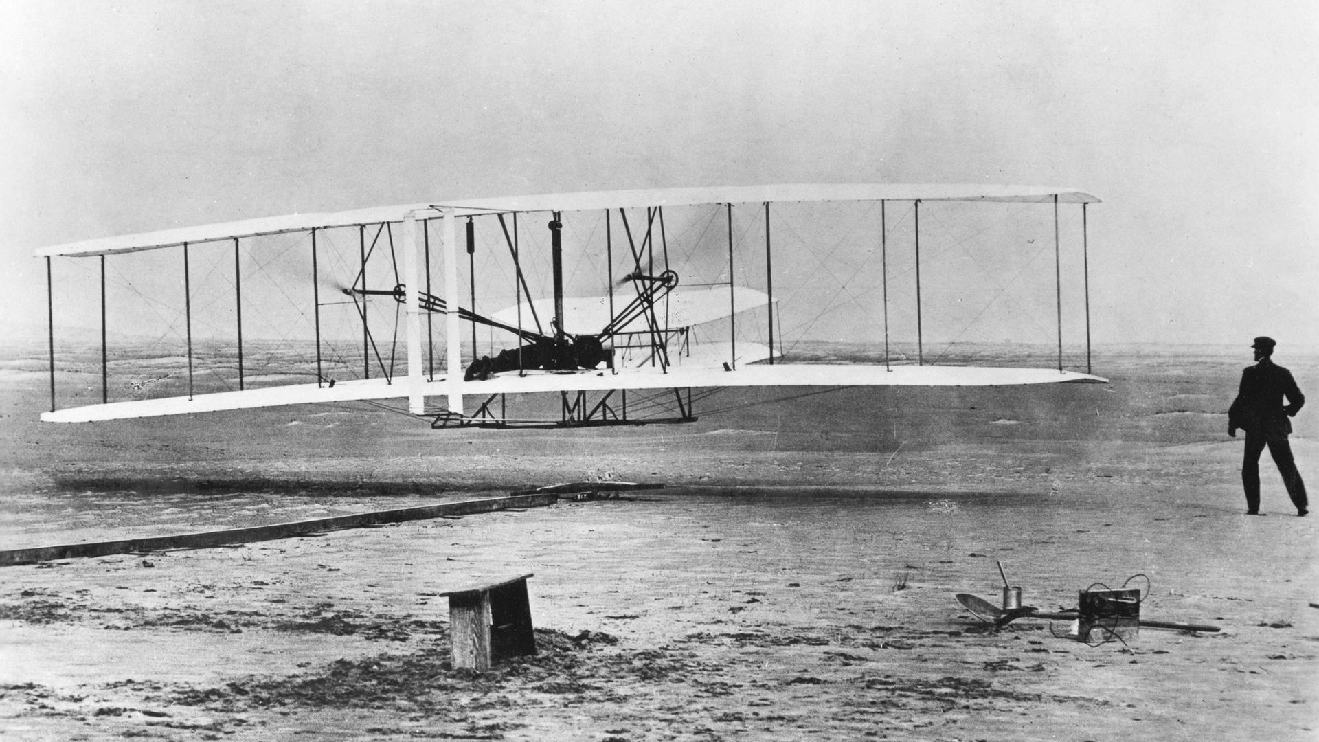 Schwarzweißfotografie des ersten Flugzeugs der Wright-Brüder.