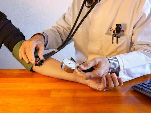 Besuch in der Praxis des Hausarztes. Arzt im Laborkittel misst den Blutdruck eines Patienten. Gesundheitswesen. Nahaufnahme 