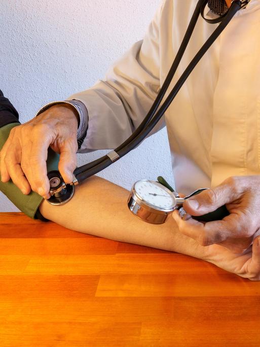 Besuch in der Praxis des Hausarztes. Arzt im Laborkittel misst den Blutdruck eines Patienten. Gesundheitswesen. Nahaufnahme 