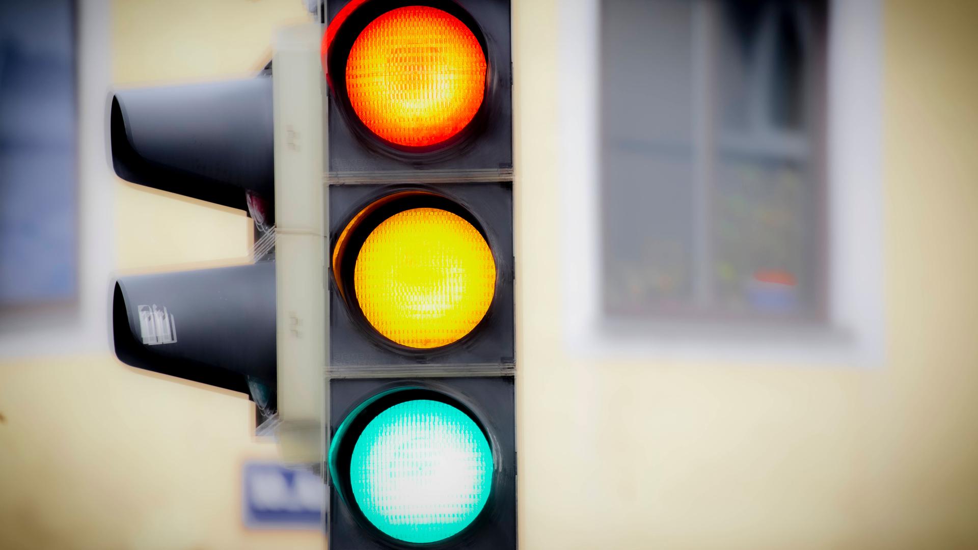 Eine Verkehrsampel leutchtet rot, gelb und grün.