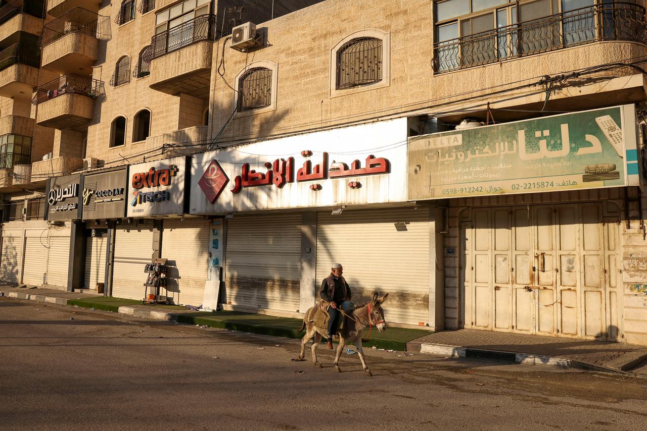 Eine Straße in Hebron, in der alle Geschäfte geschlossen sind. Nur ein Mann auf einem Esel reitet an ihnen vorbei.