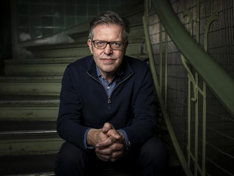 Porträtaufnahme des Soziologen Steffen Mau, der mit ernstem Blick in einem Treppenhaus sitzt