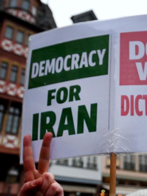 Demonstranten halten ein Schild hoch, auf dem steht: "democracy for iran" und "down with dictatorship".