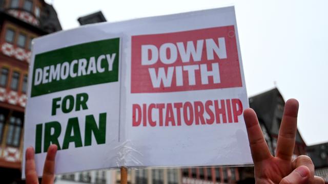 Demonstranten halten ein Schild hoch, auf dem steht: "democracy for iran" und "down with dictatorship".