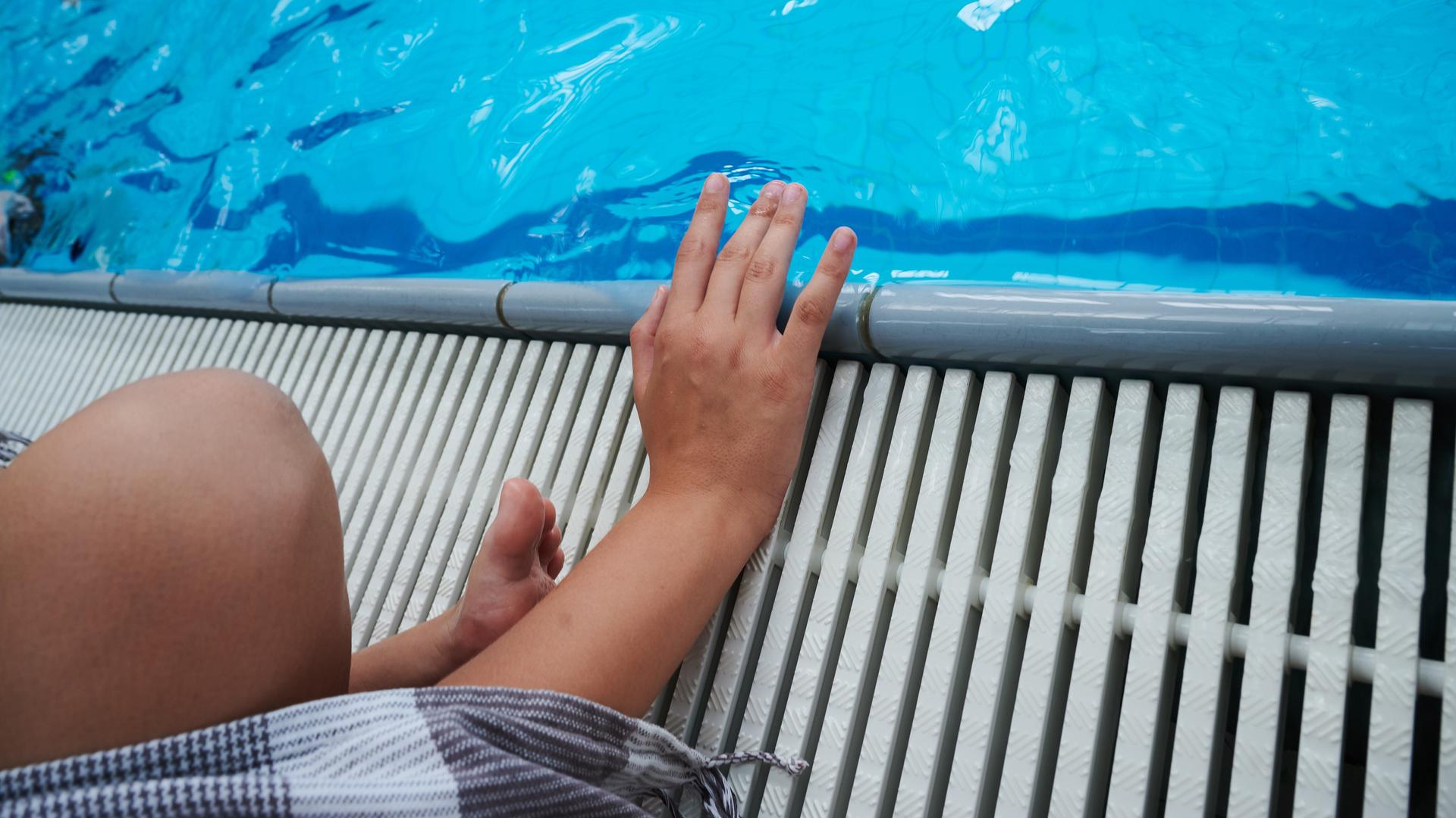 Ein Kind sitzt an einem Schwimmbecken Ein Kind sitzt an einem Schwimmbecken