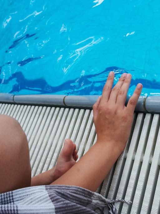 Ein Kind sitzt an einem Schwimmbecken