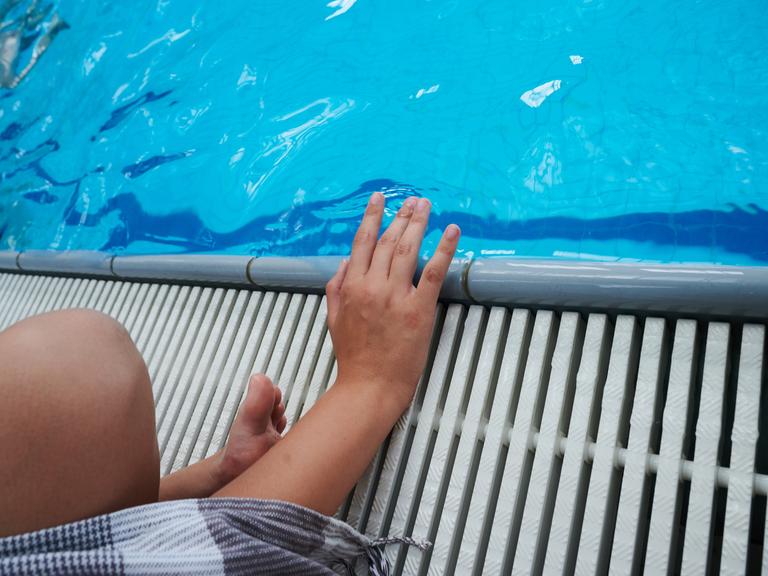 Ein Kind sitzt an einem Schwimmbecken