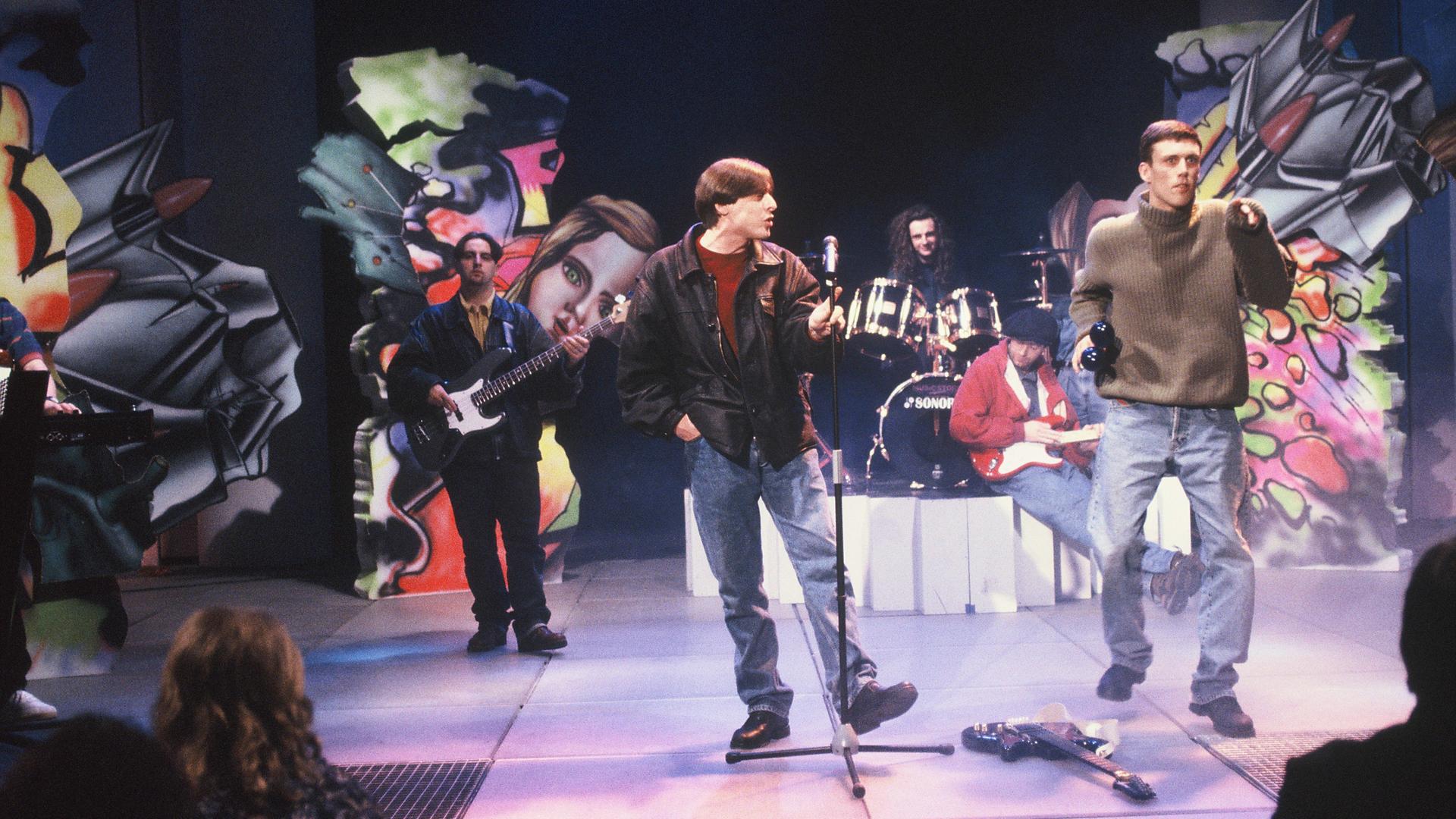 Die Band Happy Mondays bei einem Auftritt im September 1990. Paul Ryder ist hinten links am Bass zu sehen. Die Band Happy Mondays bei einem Auftritt im September 1990. Paul Ryder ist hinten links am Bass zu sehen.