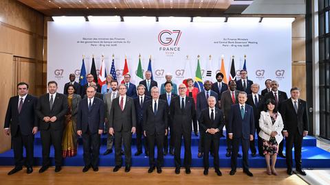 Eine Gruppe von Personen posiert beim Treffen der Finanzminister der G7-Staaten für ein Gruppenfoto. Im Hintergrund sind Flaggen mehrerer Staaten.