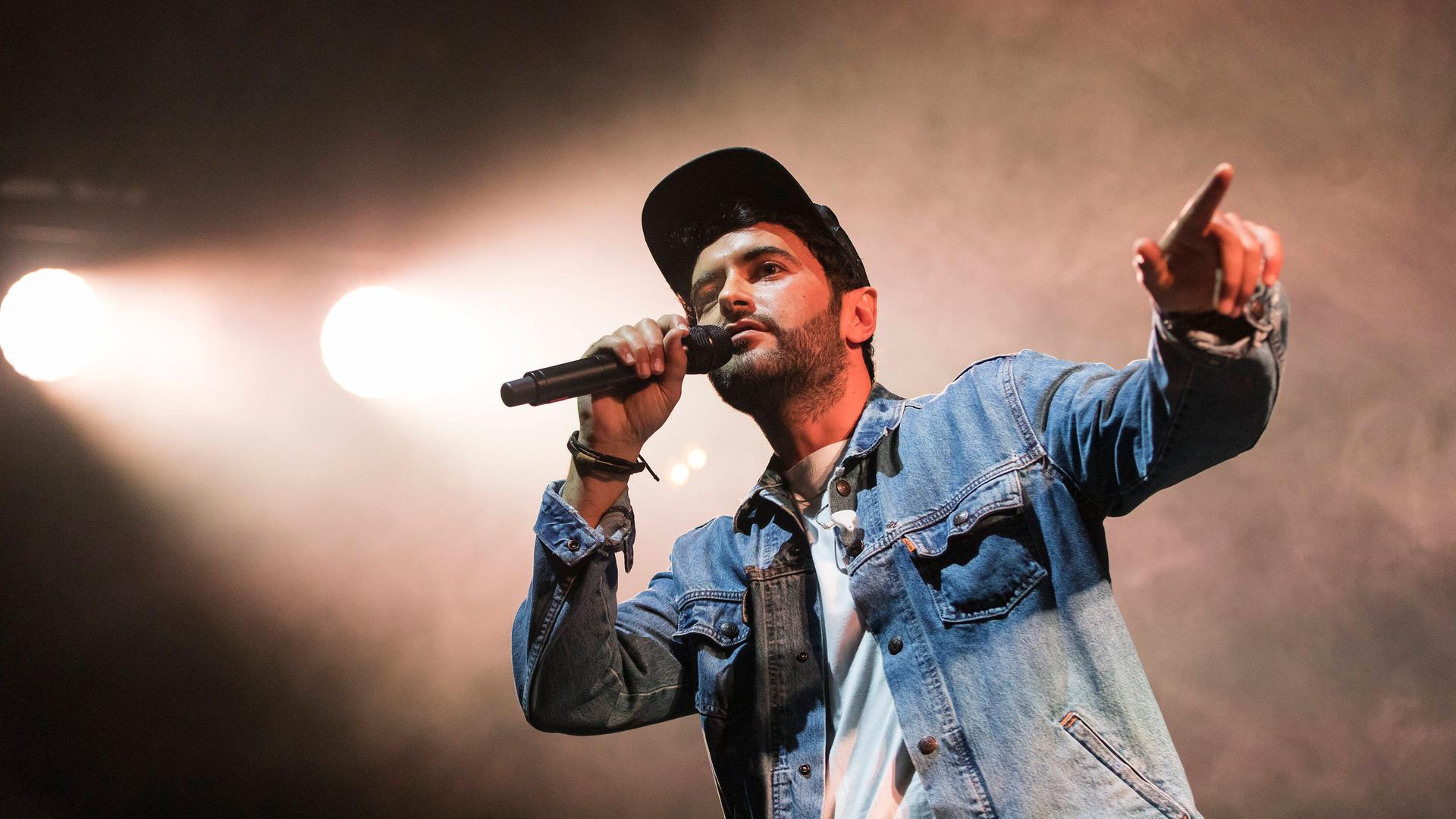 Chefket steht auf einer Bühne und singt