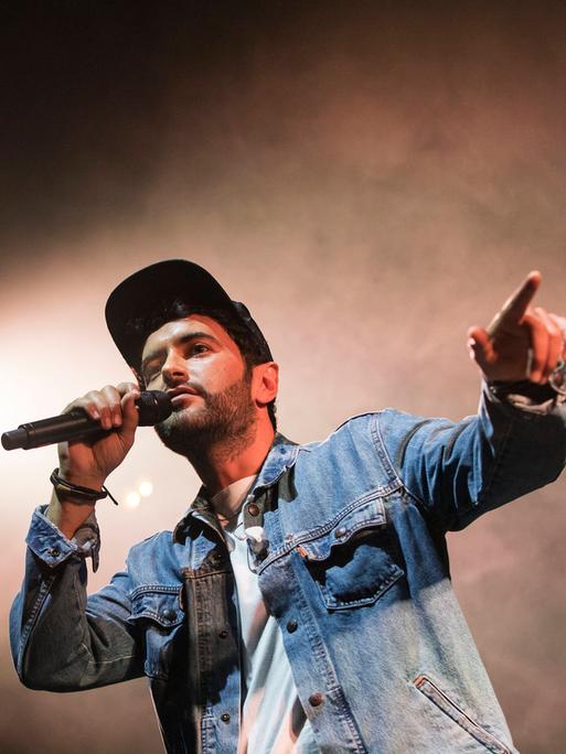 Chefket steht auf einer Bühne und singt