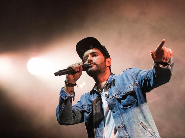 Chefket steht auf einer Bühne und singt