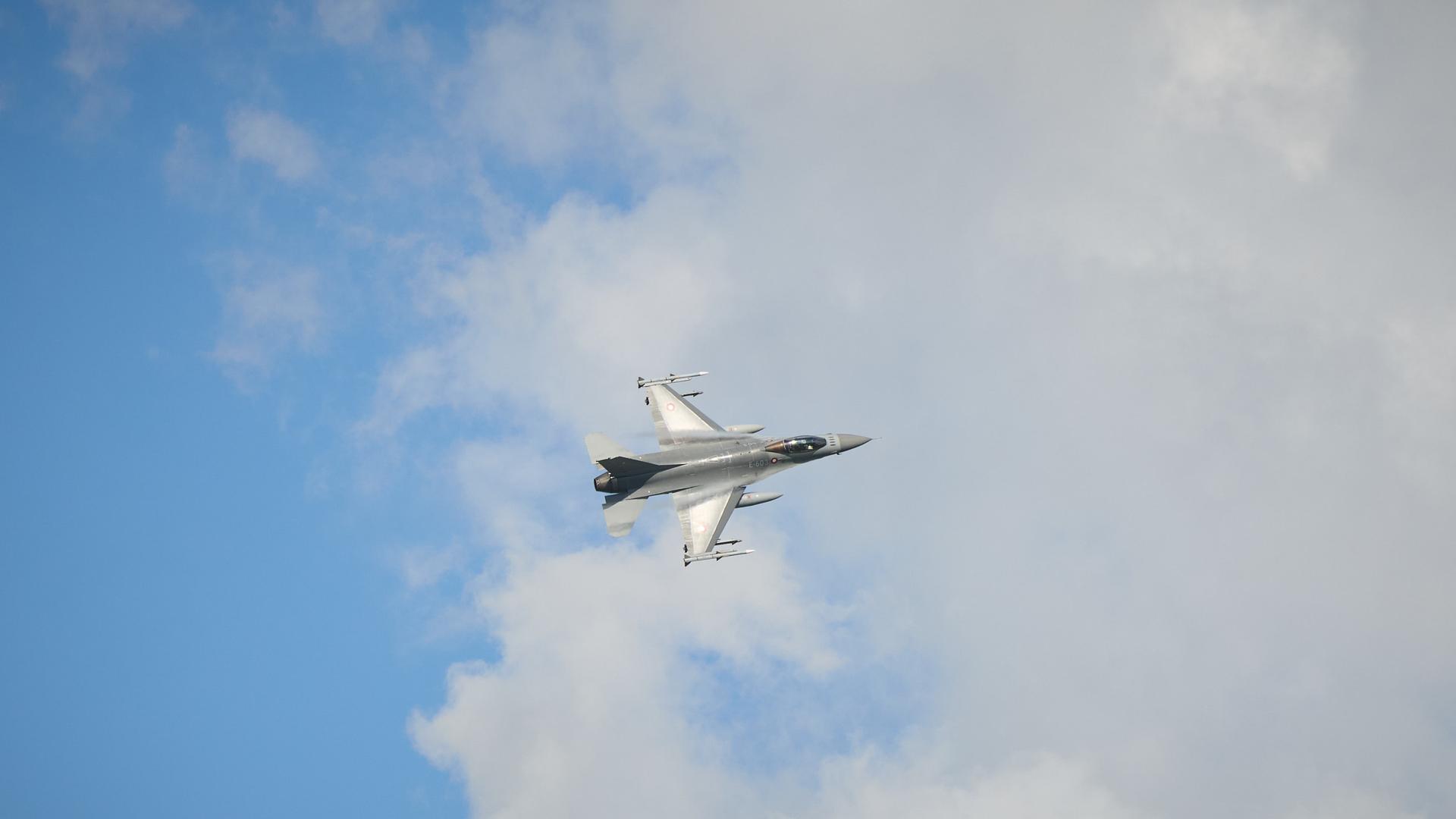 F-16-Kampfjet in der Luft vor blauem Himmel mit Wolken. 