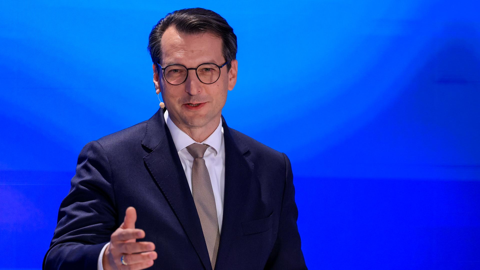 Milan Nedeljkovic spricht vor blauem Hintergrund und hält die rechte Hand nach vorne gestreckt. Milan Nedeljkovic spricht vor blauem Hintergrund und hält die rechte Hand nach vorne gestreckt.