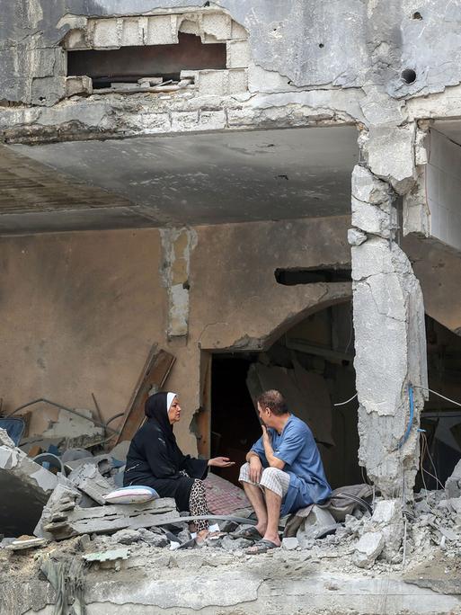 10. Oktober 2023, Gaza, Palästina: Palästinenser sitzen nach israelischen Angriffen in Gaza-Stadt zwischen den Trümmern eines beschädigten Wohngebäudes. Israel hat nach eigenen Angaben die Grenzgebiete des Gazastreifens von der Hamas zurückerobert. Am 10. Oktober, dem vierten Tag der zermürbenden Kämpfe seit dem Überraschungsangriff der Islamisten, wurden mehr als 3.000 Menschen getötet.