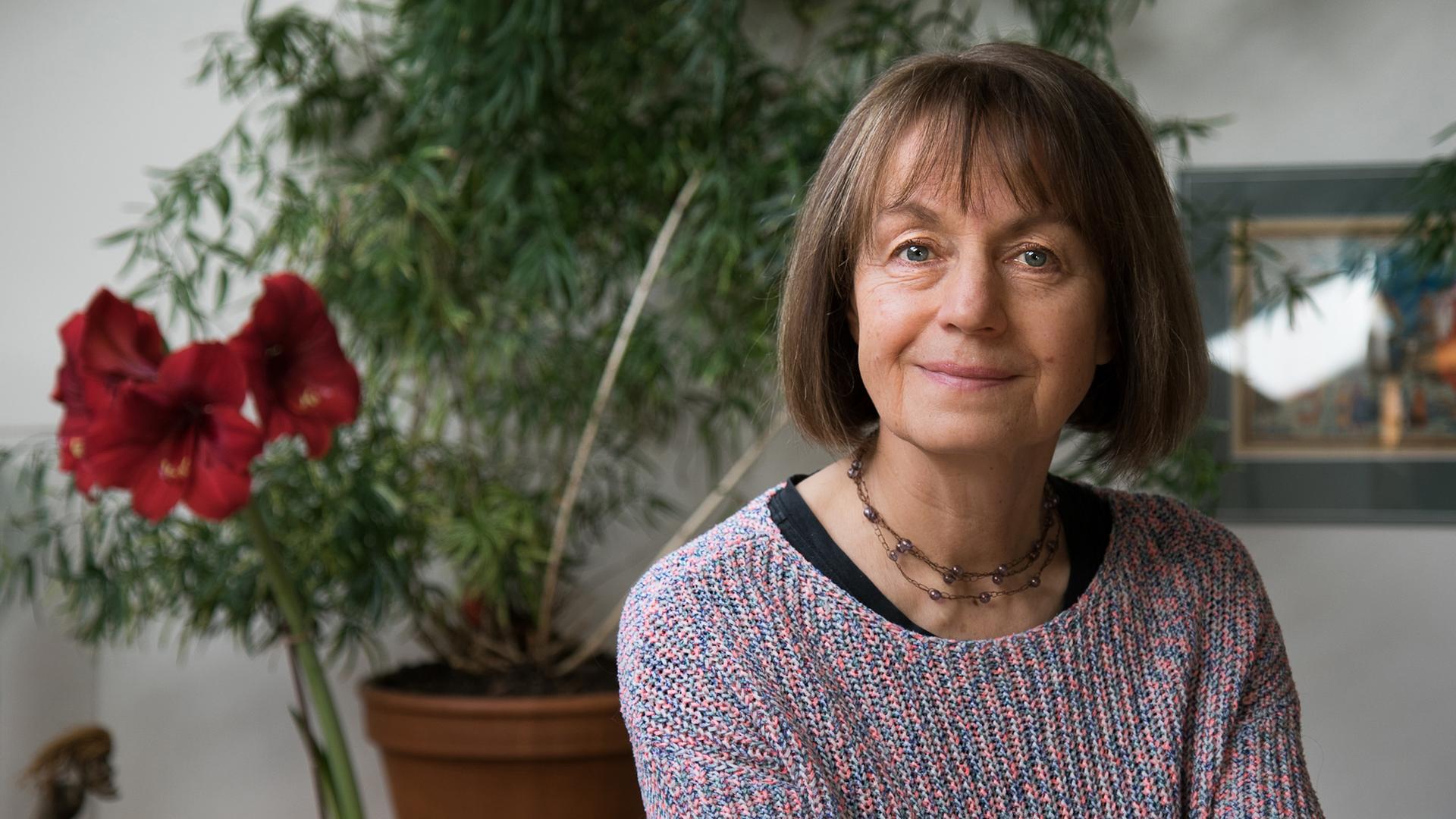 Iva Procházková lächelt in die Kamera. Sie hat einen mittelbraunen Bob und trägt einen bunten Strickpullover.