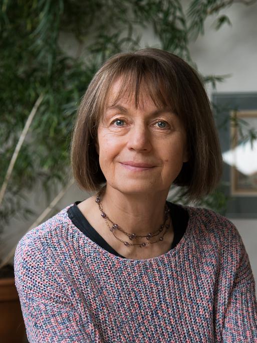 Iva Procházková lächelt in die Kamera. Sie hat einen mittelbraunen Bob und trägt einen bunten Strickpullover.