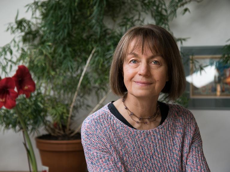 Iva Procházková lächelt in die Kamera. Sie hat einen mittelbraunen Bob und trägt einen bunten Strickpullover.