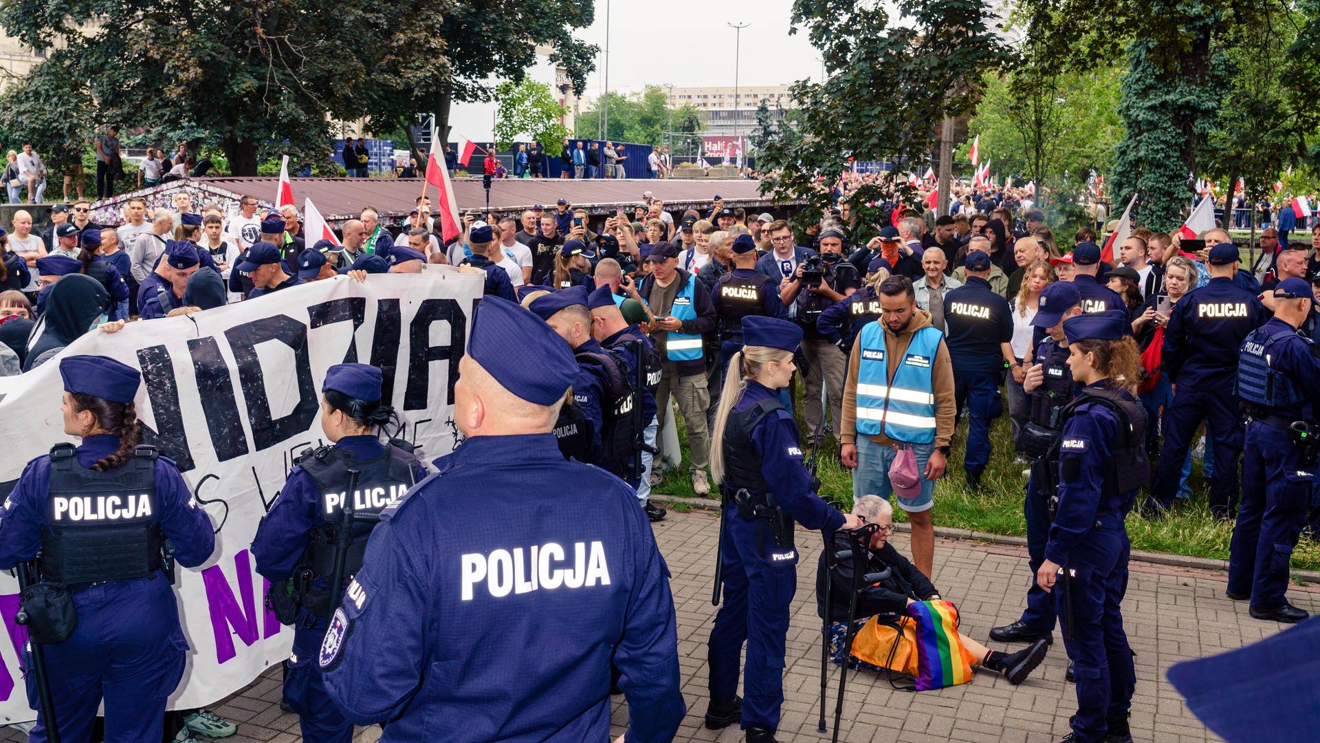 Polizisten stehen vor Demonstranten in Warschau