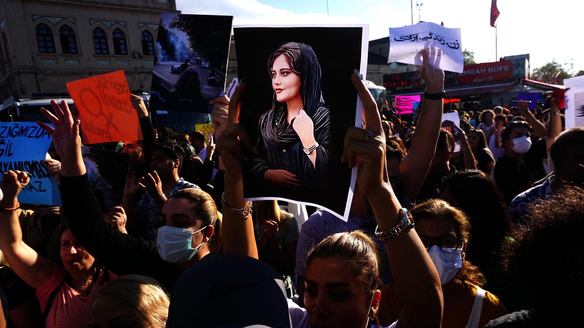 Menschenmassen halten während einer Demonstration in den Straßen Plakate von Mahsa Amini hoch.