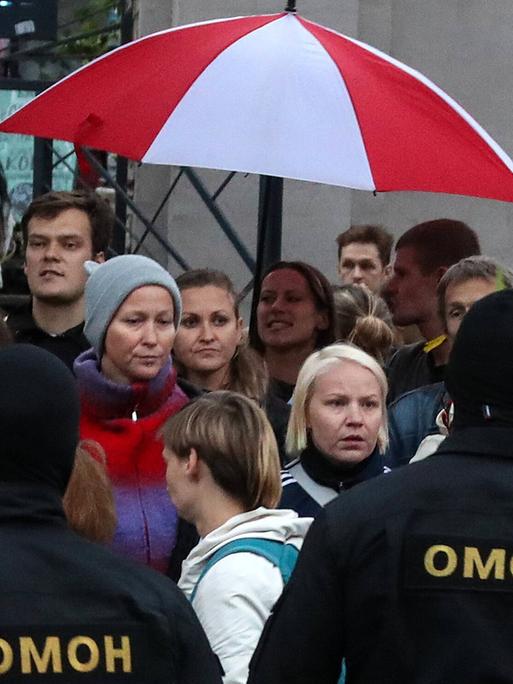 Omon-Polizisten bedrängen demonstrierende Frauen in Minsk am 08.09.2020, sie halten einen rotweißen Regenschirm über ihre Köpfe Omon-Polizisten bedrängen demonstrierende Frauen in Minsk am 08.09.2020, sie halten einen rotweißen Regenschirm über ihre Köpfe
